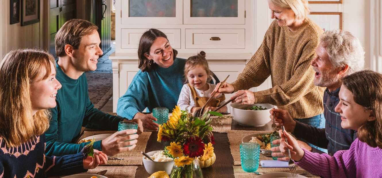 A happy family is gathered at the table enjoying a meal.