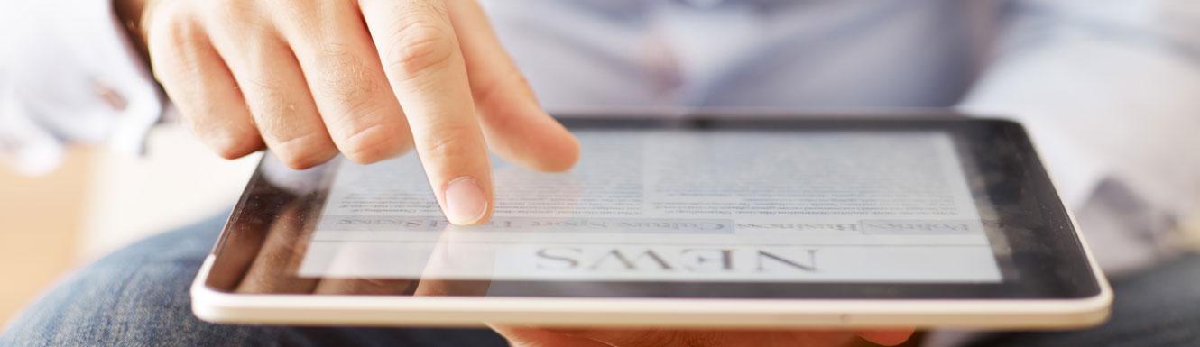 A man is reading news on an electronic mobile device or tablet.