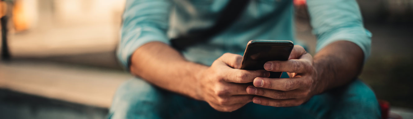 A man is sitting on a bench using his cellphone.