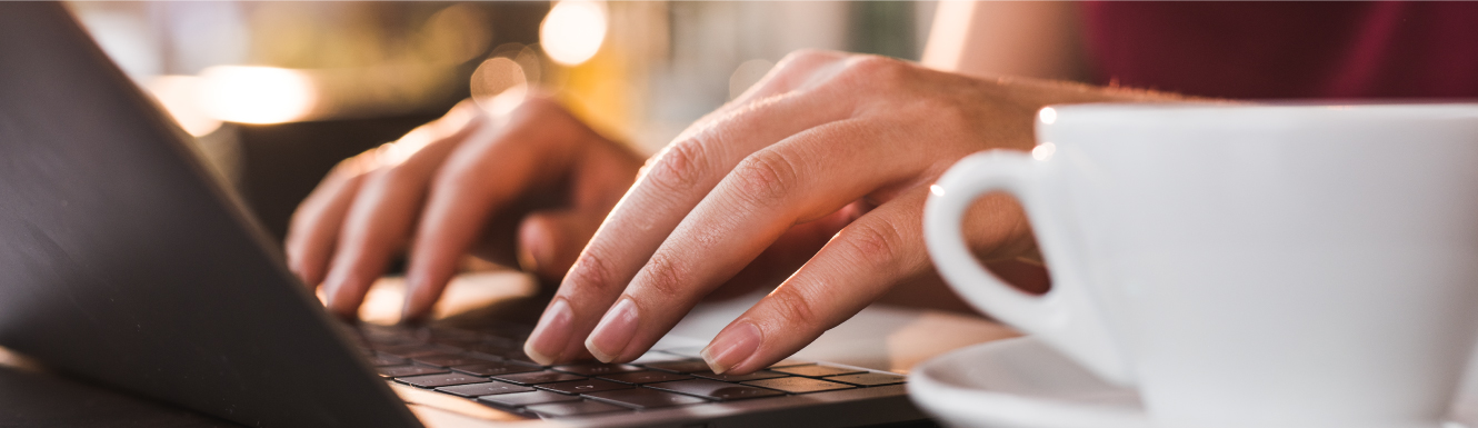 A woman typing on her laptop with coffee