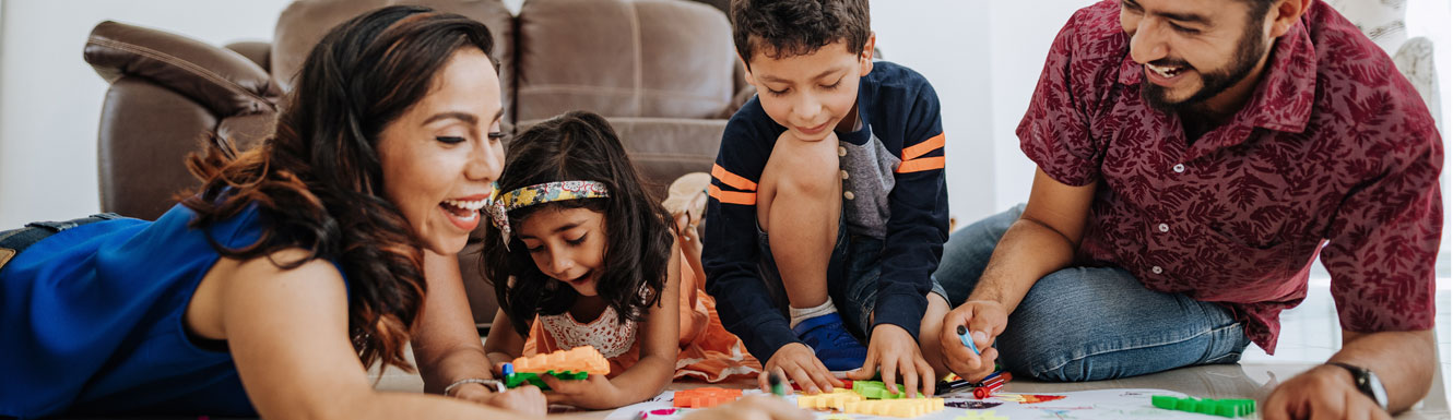 A happy young family is on the living room floor with crayons and coloring books.