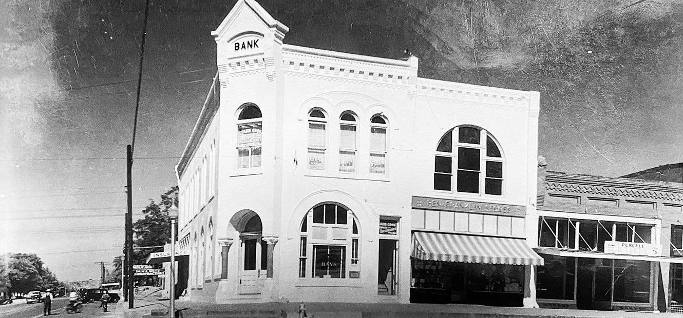 A picture of the original McClain Bank building with lightly painted brick, believed to be from the 1940s.
