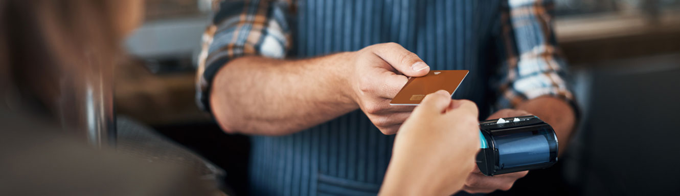 A small business owner is accepting payment from a woman using a debit or credit card.